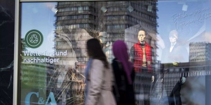Passanten gehen an einem Schaufenster am Berliner Alexanderplatz vorbei. Foto: Carsten Koall/dpa Passanten gehen an einem Schaufenster am Berliner Alexanderplatz vorbei. Foto: Carsten Koall/dpa