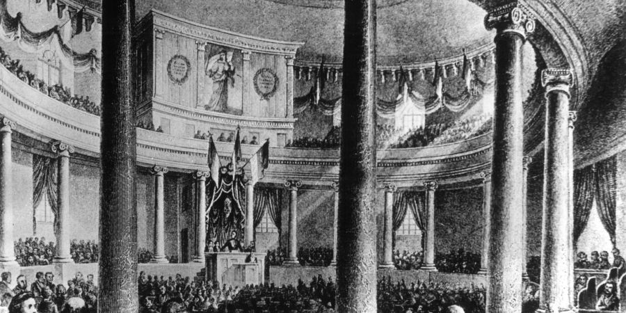 Die zeitgenössische Darstellung zeigt die erste Sitzung der Nationalversammlung, die von ihrem Präsidenten Heinrich von Gagern am 18. Mai 1848 in der Frankfurter Paulskirche eröffnet wurde.