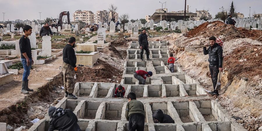 dpatopbilder - Syrer heben entlang der türkisch-syrischen Grenze Gräber für ihre Angehörigen aus, die bei dem verheerenden Erdbeben ums Leben gekommen sind. Foto: Anas Alkharboutli/dpa