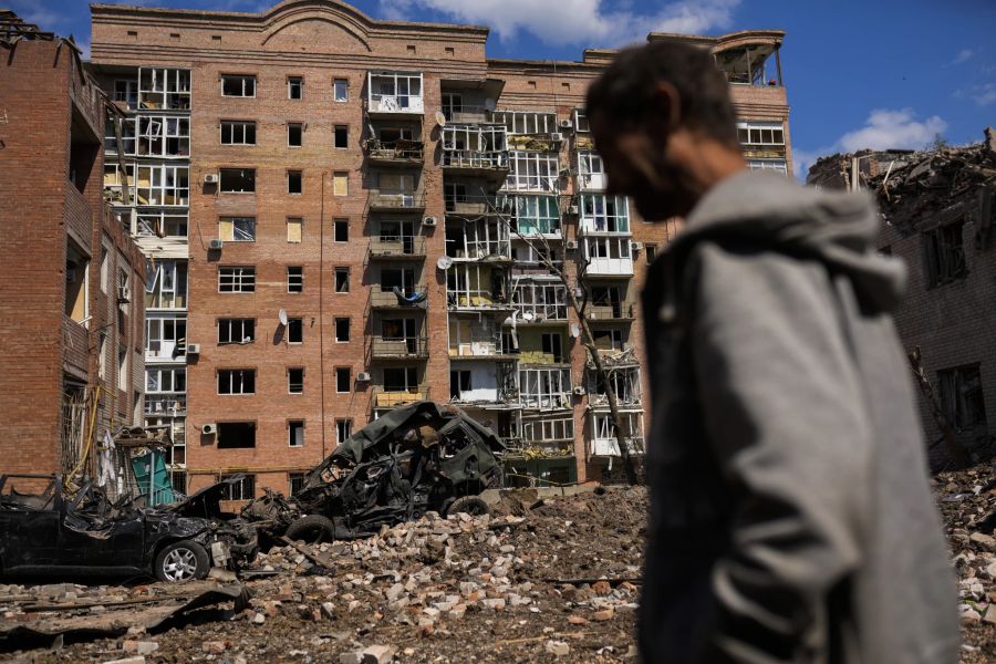 Ein Mann geht neben schwer beschädigten Gebäuden und zerstörten Autos nach russischen Angriffen in Bakhmut, Region Donezk, Ostukraine, Dienstag, 24. Mai 2022.