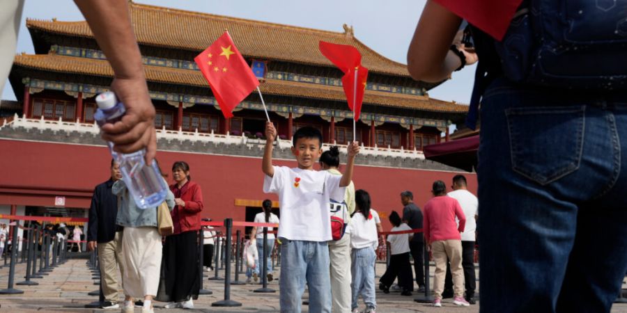 ARCHIV - Ein Kind posiert für Fotos mit chinesischen Nationalflaggen vor der Verbotenen Stadt während des Nationalfeiertags. Foto: Ng Han Guan/AP/dpa
