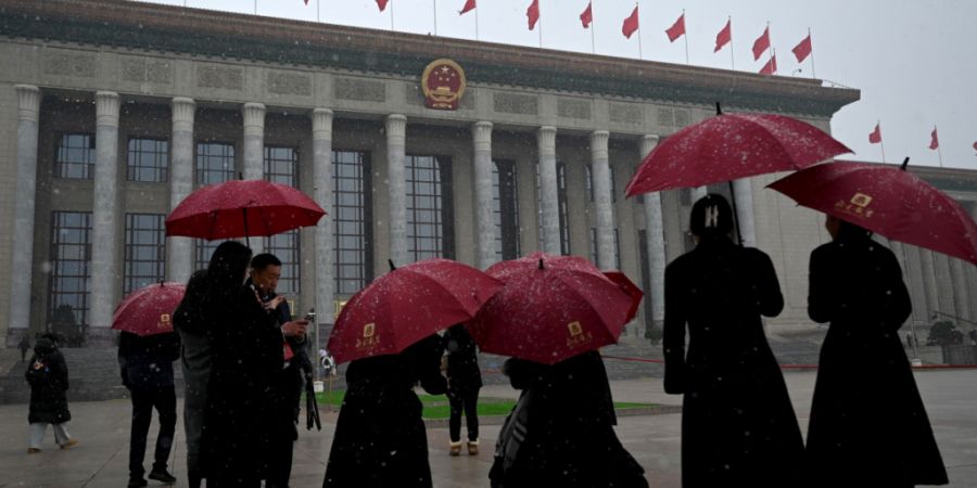 dpatopbilder - Menschen laufen unter Schneefall zur Großen Halle des Volkes. Foto: Johannes Neudecker/dpa