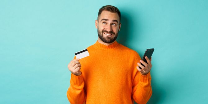 Nachdenklicher Mann mit Smartphone und Kreditkarte