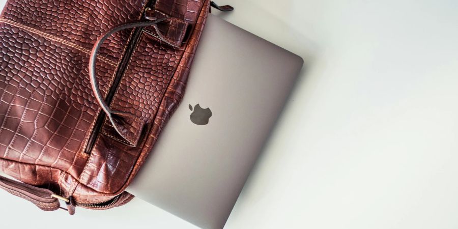 Apple Laptop schaut aus einer Ledertasche raus