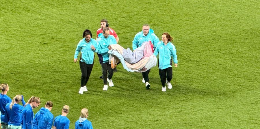 Die Volunteers verlassen das Feld, am unteren Bildrand sind isländische Spielerinnen zu sehen.