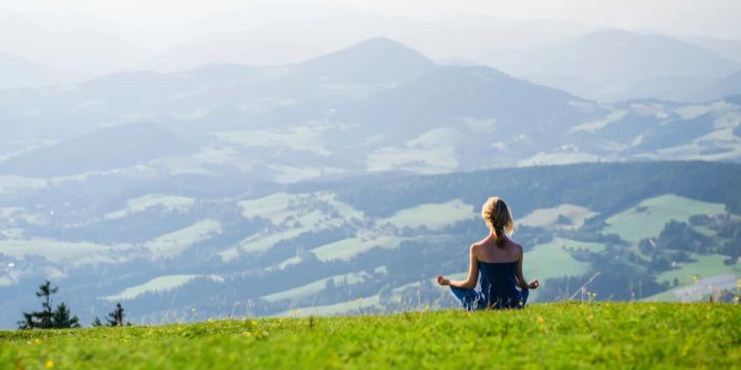 Frau Meditation Wiese Ausblick Bergkulisse