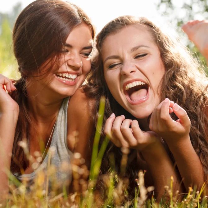 Freundinnen lachen im Gras.