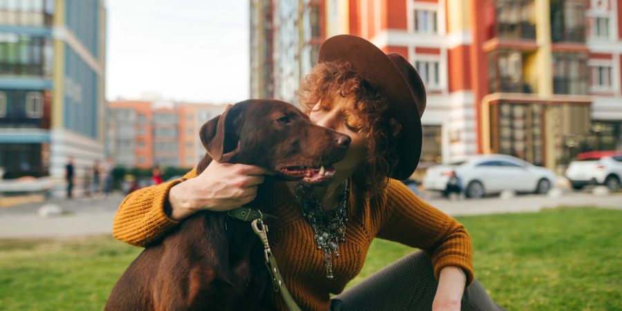 Frau mit Hund auf Gras, urbane Gegend