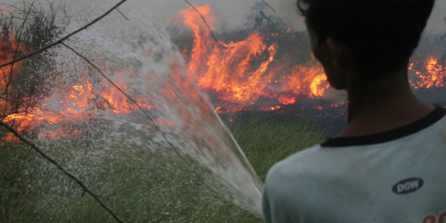 Ein Freiwilliger sprüht Wasser, um einen Waldbrand in Indonesien zu löschen. Foto: Muhammad Hatta/AP/dpa