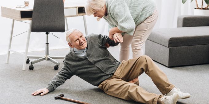 Nach dem Schlaganfall wieder auf die Beine zu kommen, ist nicht einfach, geht aber mit guter Unterstützung und dem richtigen Lifestyle. Frau hilft altem Mann vom Boden auf. Schlaganfall.