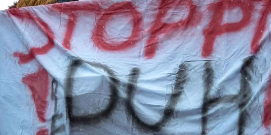 Ein Banner mit der Aufschrift «Stoppt DUH!» (Deutsche Umwelthilfe) hängt während einer Demonstration gegen das Dieselfahrverbot in Stuttgart an einer Brücke. Foto: Sebastian Gollnow