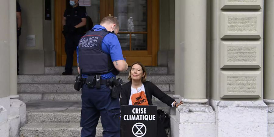 Ein Polizist kontrolliert die Identität einer Extinction Rebellion-Aktivistin, die sich am Bundeshaus angeklebt hatte.