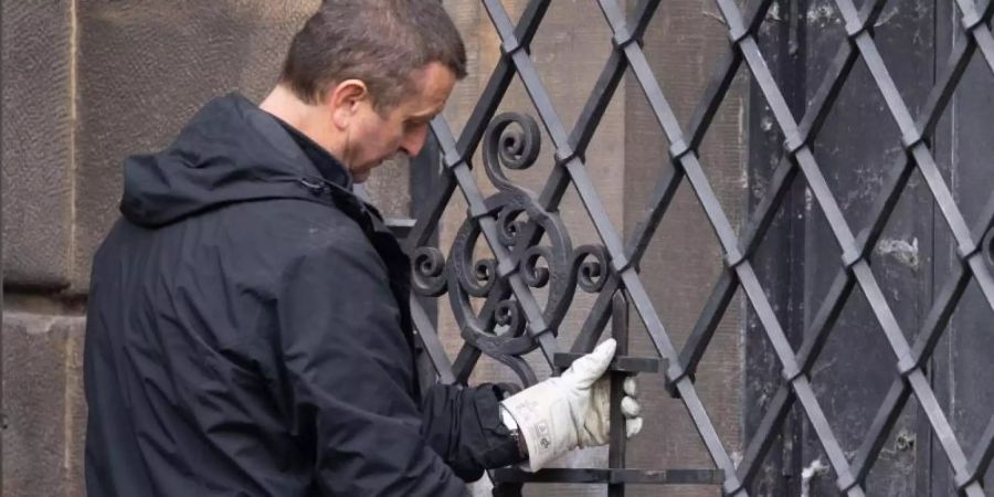 Ein Mitarbeiter einer Restaurierungsfirma arbeitet an dem bei einem Einbruch durchtrennten Gitterfenster des Grünen Gewölbes. Foto: Sebastian Kahnert/dpa-Zentralbild/dpa