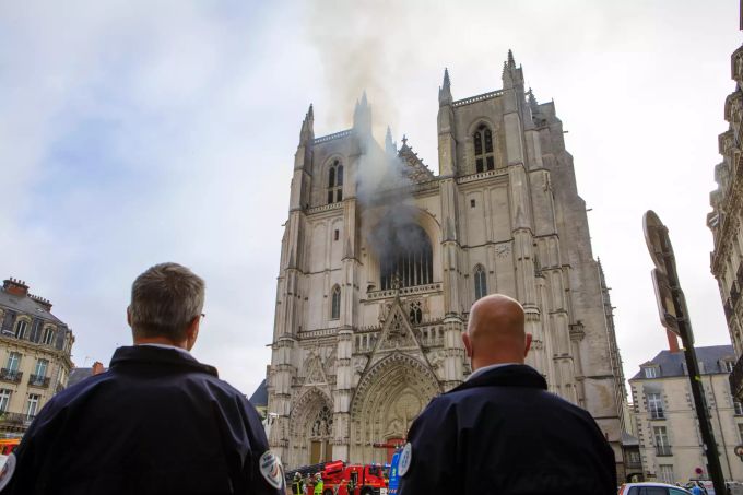 08.02.2019, Frankreich, Nantes: Polizisten betrachten, wie Rauch aus einem Fenster der Kathedrale Saint-Pierre-et-Saint-Paul steigt. In der Kathedrale der westfranzösischen Stadt Nantes war ein Feuer ausgebrochen. (zu dpa "Tatverdächtiger nach Brand in französischer Kathedrale in U-Haft") Foto: Laetitia Notarianni/AP/dpa +++ dpa-Bildfunk +++ Brand in Kathedrale von Nantes