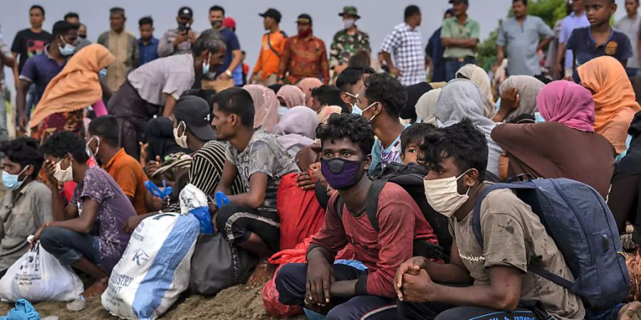 Geflüchtete Rohingya sitzen am Strand der Provinz Lancok, nachdem sie mit einem Boot dort angekommen sind. Indonesische Fischer entdeckten die hungernden und geschwächten Rohingya-Muslime auf dem Holzboot, das vor Indonesiens nördlichster Provinz Aceh trieb. Foto: Zik Maulana/AP/dpa