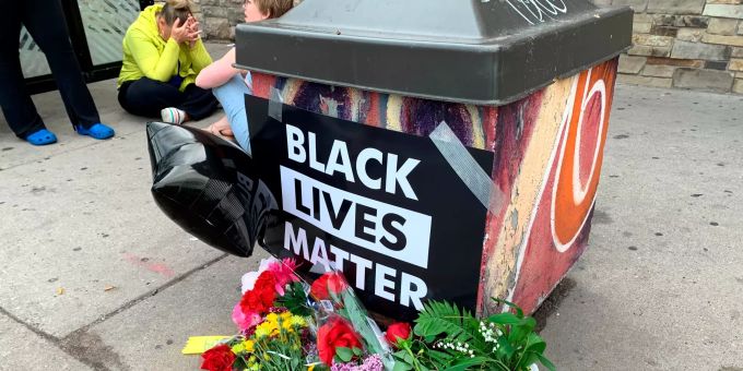Trauernde versammeln sich um ein provisorisches Denkmal, an dem ein Schild der Aktivistenbewegung «Black Lives Matter» hängt, in dessen Nähe am Vortag ein Mann afroamerikanischer Abstammung von der Polizei festgehalten wurde. Der weisse Polizist kniete auf dem Hals des Mannes, welcher mehrmals darauf aufmerksam machte, dass er nicht atmen könne. Der Mann starb später im Spital. Polizeigewalt