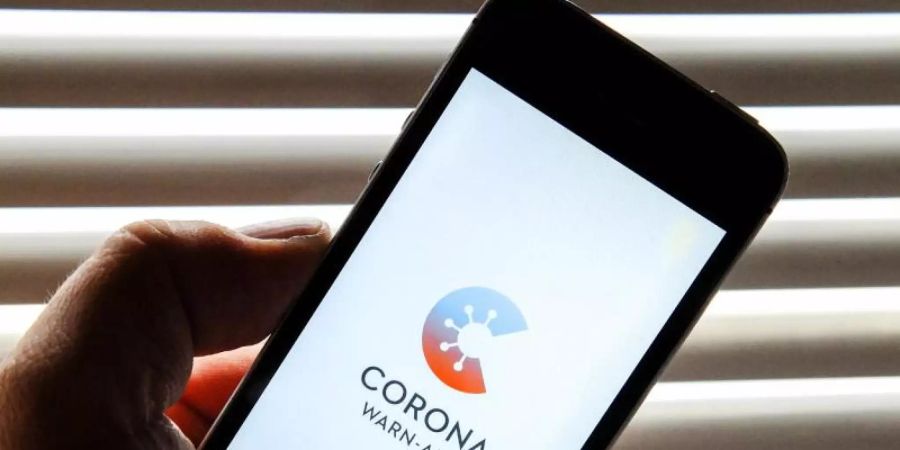 Auf dem Bildschirm eines Apple iPhone SE ist der vom Presse- und Informationsamt der Bundesregierung herausgegebene Startschirm einer Corona Warn-App abgebildet. Foto: Stefan Jaitner/dpa