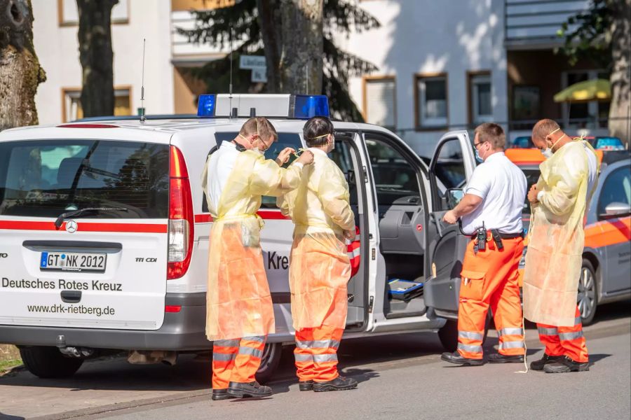 Helfer des Roten Kreuzes ziehen sich Mund-Nasenschutz und Schutzkleidung an und bereiten sich auf einen Einsatz vor. Auch ein Grossaufgebot von Polizisten wurde zu Tönnies in Gütersloh (D) geschickt.