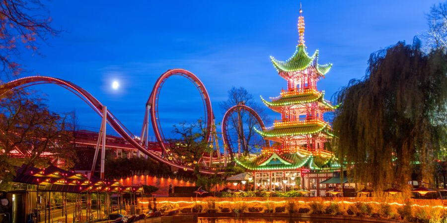 Chinesischer Turm und Achterbahn im beleuchteten Tivoli Vergnüngspark in Kopenhagen.