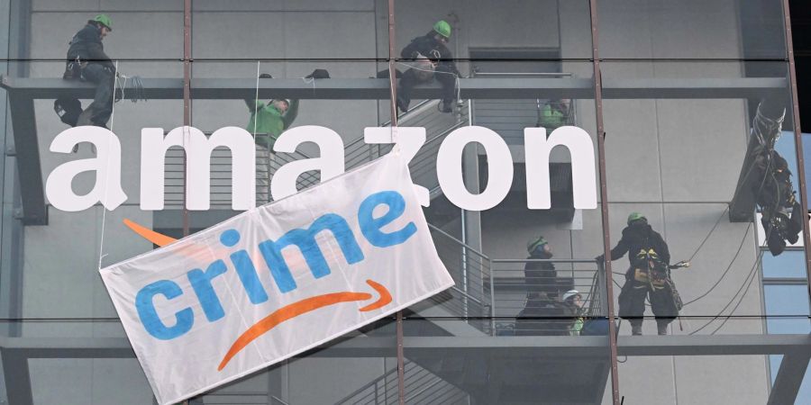 Greenpeace-Aktive hängen während der Rabattaktion Black Friday ein Plakat gegen die Ressourcenverschwendung des Online-Versandhändlers Amazon an dessen Gebäude in München auf.