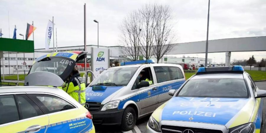 Fahrzeuge der Polizei stehen vor dem Werk eines Getränkeherstellers, wo eine Serie explosiver Postsendungen begannn. Jetzt wird wird einem 66-jährigen Elektriker der Prozess gemacht. Foto: Rene Priebe/dpa