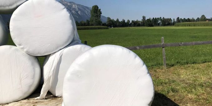 Gestapelte Siloballen auf dem Rasen. Ballenwickelgerät