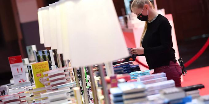 Eine Mitarbeiterin der Frankfurter Buchmesse steht vor der Eröffnungspressekonferenz der Frankfurter Buchmesse an einem Buchstand in der Festhalle. Foto: Arne Dedert/dpa pool/dpa Eine Mitarbeiterin der Frankfurter Buchmesse steht vor der Eröffnungspressekonferenz der Frankfurter Buchmesse an einem Buchstand in der Festhalle. Foto: Arne Dedert/dpa pool/dpa