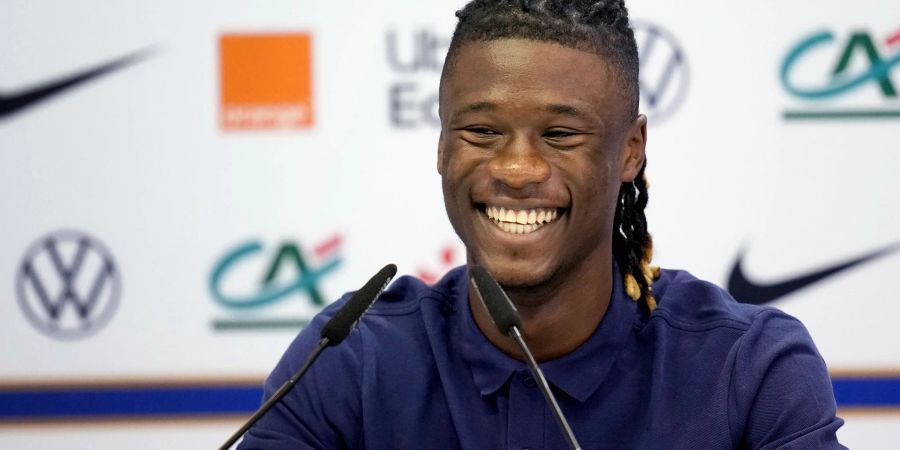 Der französische Nationalspieler Eduardo Camavinga lächelt, während er bei einer Pressekonferenz auf dem Podium sitzt.