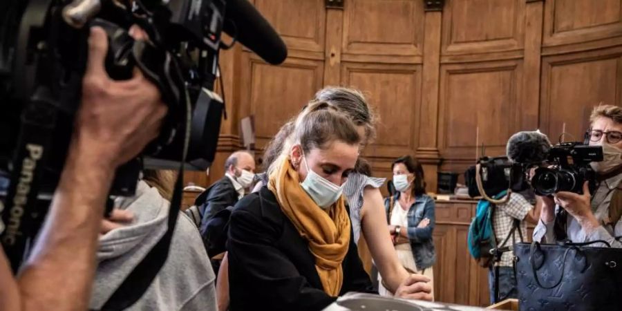 Die Angeklagte Valerie Bacot (M) kommt flankiert von ihrer Familie und umgeben von Journalisten im Gerichtsgebäude an. Foto: Jeff Pachoud/AFP/dpa