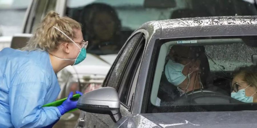 Eine Mitarbeiterin einer Teststation bereitet Autofahrer auf einen COVID-19-Test vor. Foto: Mark Baker/AP/dpa