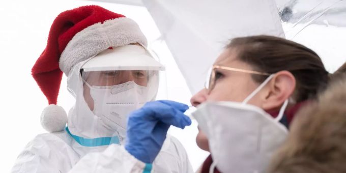 Eine ehrenamtliche, weihnachtliche DRK-Helferin führt in einer Teststation in Göppingen einen Corona-Schnelltest an einer Frau durch. Kostenlose Corona-Schnelltests zu Weihnachten