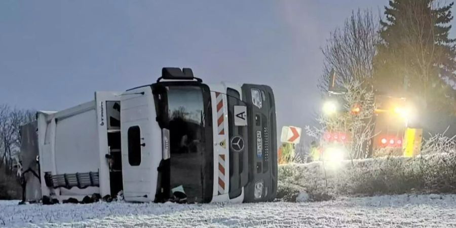 Umgekippter Mülllaster bei Bretzfeld in Baden-Württemberg. Auf eisglatter Fahrbahn war der Lastwagen zuvor von der Strasse gerutscht. Foto: Julian Buchner/dpa