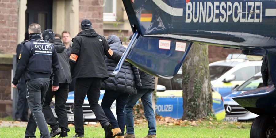 Eine Person (2.v.r.) wird von Polizisten aus einem Hubschrauber gebracht. Die Bundesanwaltschaft hat am Mittwochmorgen mehrere Menschen aus der sogenannten Reichsbürgerszene im Zuge einer Razzia festnehmen lassen.