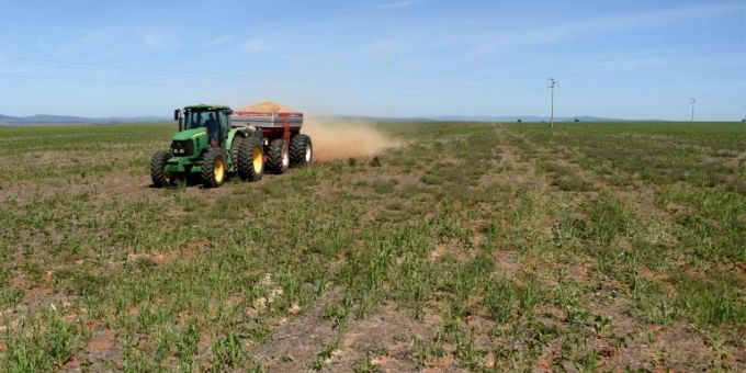 Bauer auf einem Feld bringt Dünger aus Bauer auf einem Feld bringt Dünger aus