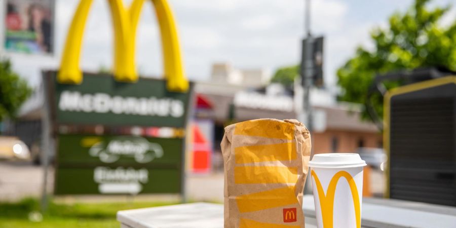 Eine McDonald's To-Go-Tüte und ein dazugehöriger To-Go-Becher stehen vor einer Tübinger McDonald's Filiale.