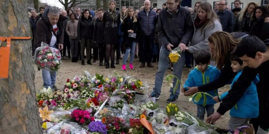 Trauernde legen Blumen in der Nähe des Ortes nieder, an dem das Unglück geschah. Foto: Peter Dejong/AP
