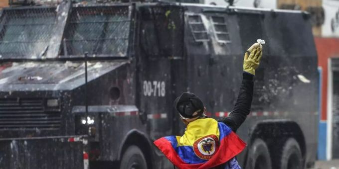 Ein Protestler wirft in einem Aussenbezirk von Bogotá einen Farbbeutel auf ein Polizeifahrzeug. Foto: Ivan Valencia/AP/dpa Ein Protestler wirft in einem Aussenbezirk von Bogotá einen Farbbeutel auf ein Polizeifahrzeug. Foto: Ivan Valencia/AP/dpa