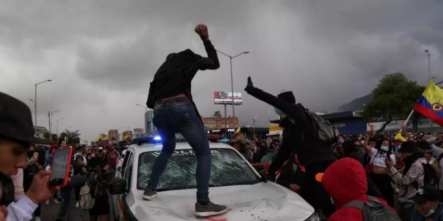 Demonstranten schlagen während des Protests in Bogota auf einen Polizeiwagen ein. Foto: Camila Diaz/colprensa/dpa