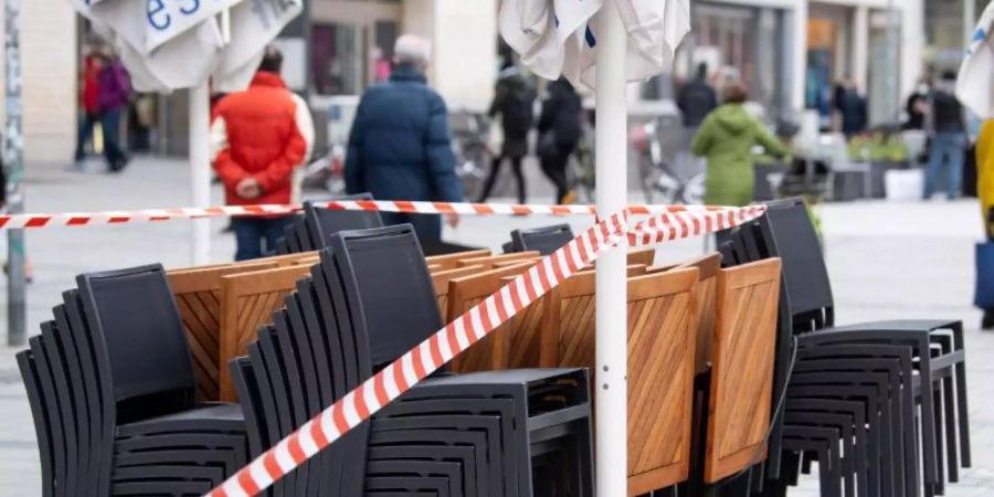 Die Tische und Stühle eines Cafes sind mit Flatterband abgesperrt. Foto: Sven Hoppe/dpa