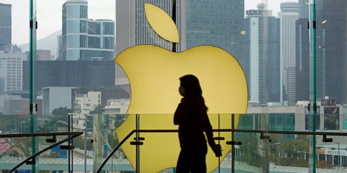 Eine Frau mit Mundschutz geht in einem Store von Apple am Apple-Logo vorbei. Apple Event iPad