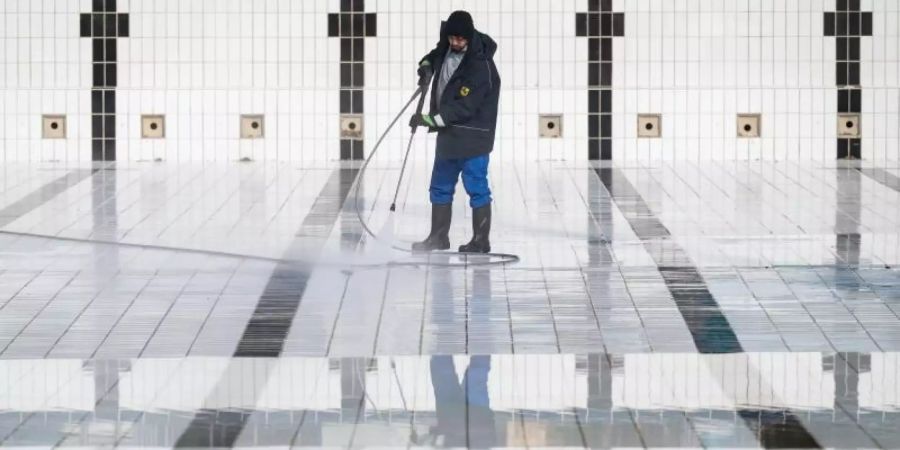 Ein Mitarbeiter reinigt ein Becken im Inselbad Untertürkheim in Stuttgart. Foto: Marijan Murat/dpa