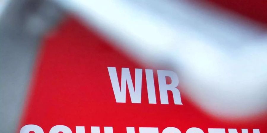 «Wir schliessen!» steht hinter einem Rollgitter an einem geschlossenen Geschäft in Düsseldorf. Foto: Martin Gerten/dpa