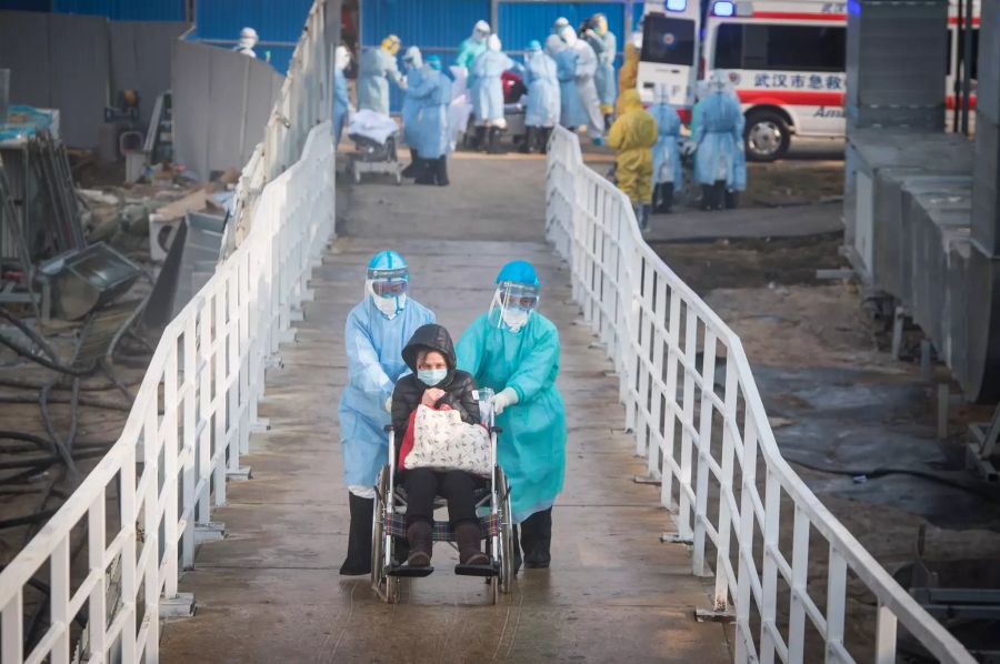 Mediziner helfen den ersten mit dem neuartigen Coronavirus infizierten Patienten beim Umzug in ihre Isolierstationen im Huoshenshan («Berg des Vulkan-Gottes»). Das Behelfskrankenhaus hat rund tausend Betten und wurde am 03.02.2020 eröffnet. Foto: Xiao Yijiu