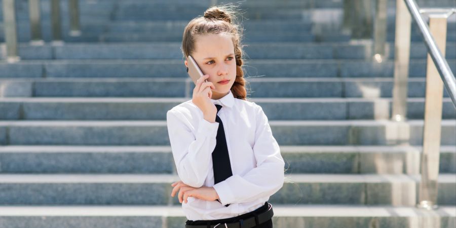 Mädchen im Business-Look mit Handy am Ohr