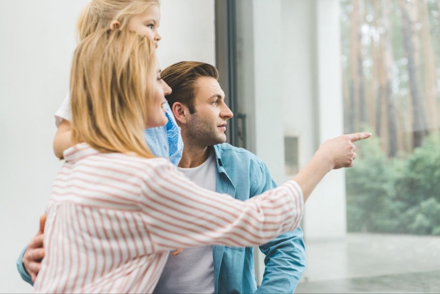 Mutter, Vater und Kind schauen aus dem Fenster