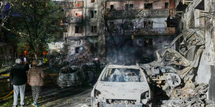 dpatopbilder - Anwohner gehen nach einem russischen Raketenangriff in Kiew, Ukraine, zwischen den Trümmern. Foto: Efrem Lukatsky/AP/dpa