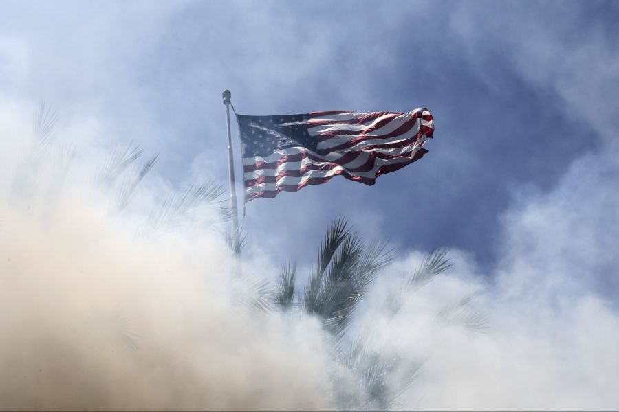 Ein amerikanisches Flaggenmotiv ist durch den Rauch von Blendgranaten zu sehen, die von Bundesbeamten abgefeuert wurden, während es in Paramount, Kalifornien, am 7. Juni 2025 zu Zusammenstössen zwischen Demonstrierenden und Bundesbehörden nach einer Razzia der Einwanderungsbehörde ICE kam.
