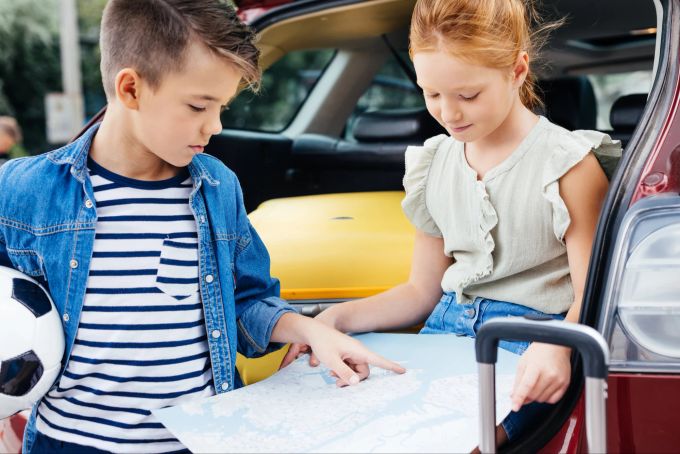Pausen sind besonders wichtig für Kinder, um die Eindrücke, die sie auf Reisen gewinnen, zu verarbeiten und neue Energie zu tanken. Kinder schauen sich eine Landkarte an