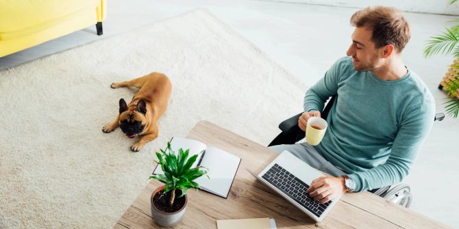 Mann im Rollstuhl arbeitet am Laptop