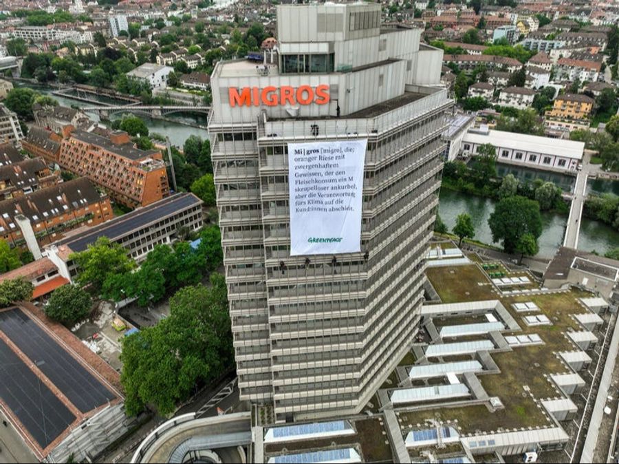 Greenpeace-Aktivisten haben in luftiger Höhe am Migros-Hauptsitz ein Banner entrollt.